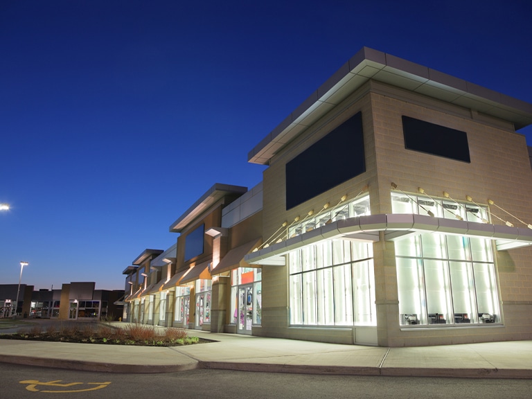 Modern commercial building at dusk with large illuminated windows.