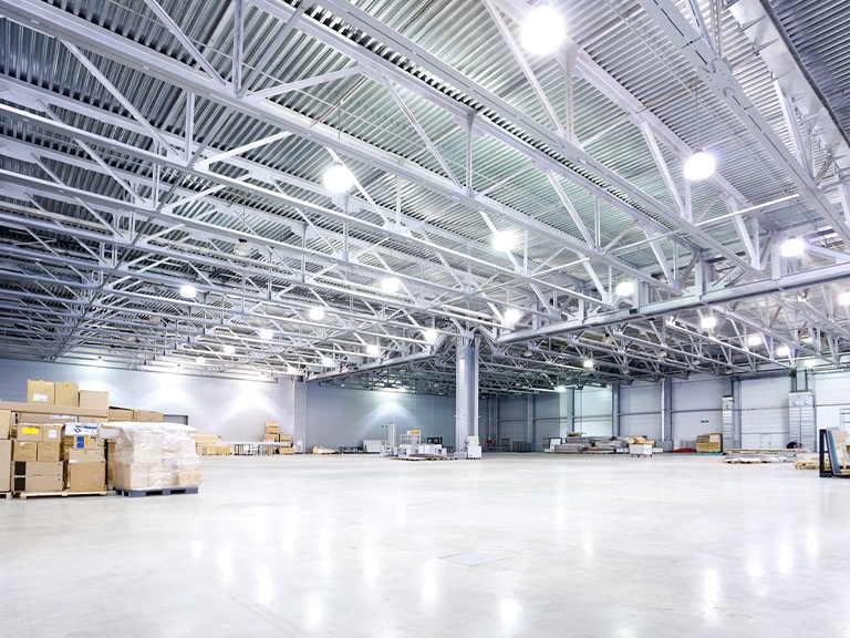 Spacious, well-lit warehouse interior with stacked pallets and high metal ceiling.